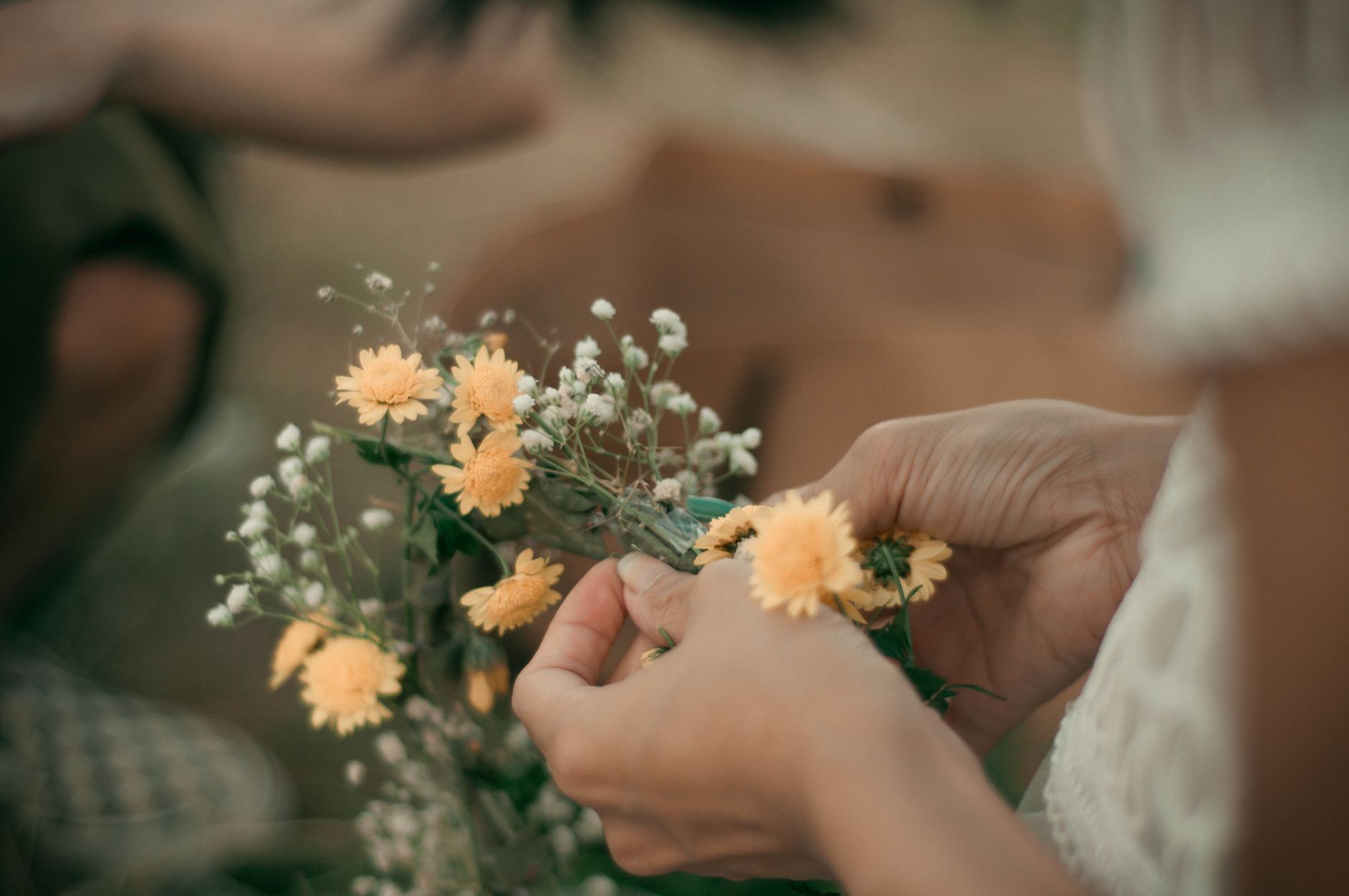 Handen schikken gele en witte bloemen tot een boeket